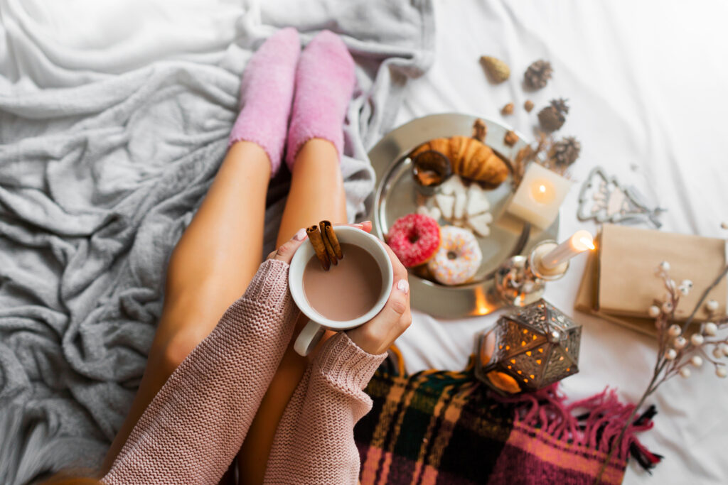 enjoying morning time in bed wearing cozy sweat and socks holding cool coffee mug